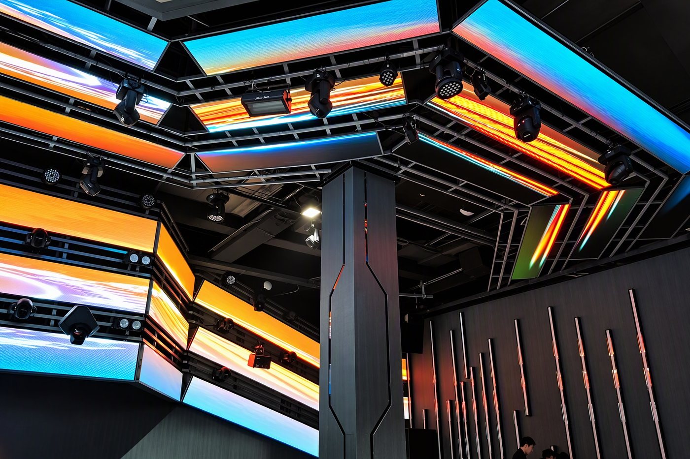 Ceiling of interlocking hexagonal LED strips casting warm and cool light across a dark venue